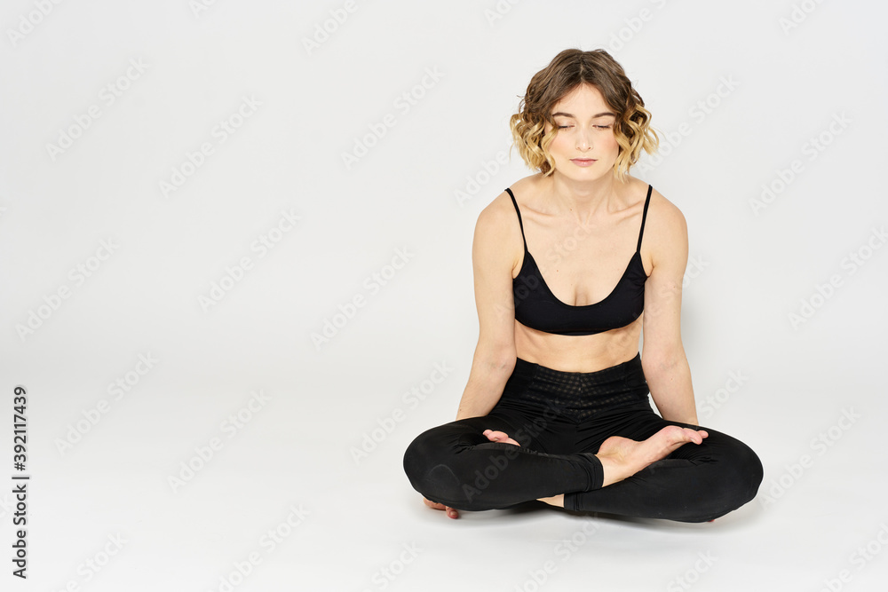 Woman in leggings meditate in a light room with her legs crossed yoga asana Woman in leggings meditate in a light room with her legs crossed yoga asana