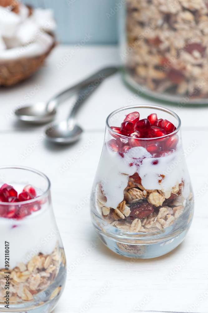 Homemade yougurt with granola and pomegranate fruit in glasses on white wooden table. Healthy breakfast. Homemade yougurt with granola and pomegranate fruit in glasses on white wooden table. Healthy breakfast.