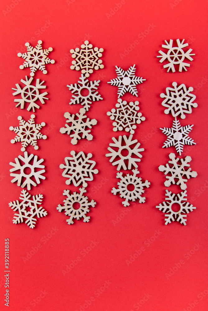 Smal wooden snowflakes lying in a row on red background Smal wooden snowflakes lying in a row on red background