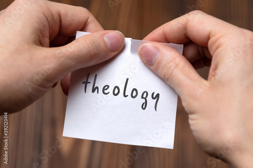 Hands tearing off paper with inscription theology photo