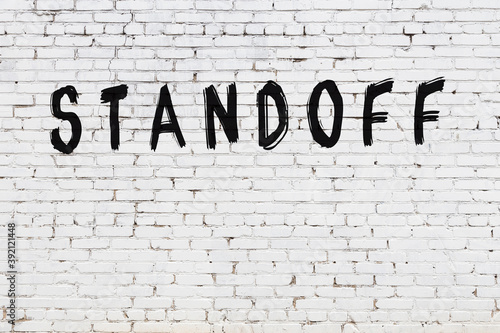 Inscription standoff painted on white brick wall