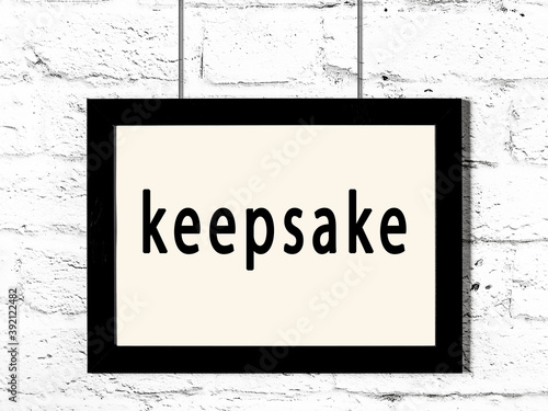 Black frame hanging on white brick wall with inscription keepsake