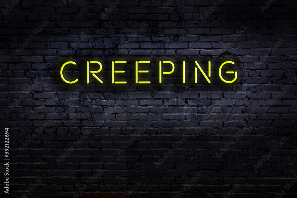 Neon sign. Word creeping against brick wall. Night view Stock