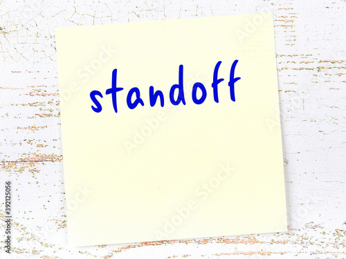 Φωτογραφία Yellow sticky note on wooden wall with handwritten word standoff