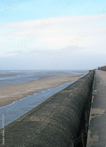 perspective view of the seawall in blackpool with the beach at low tide in sunlight with the beach and sea