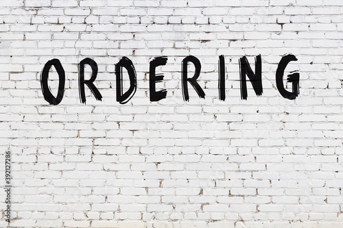 Inscription ordering painted on white brick wall