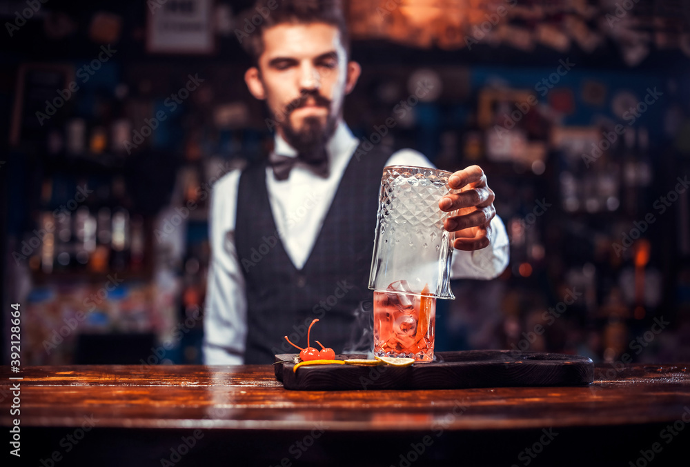 Bearded bartender makes a cocktail on the bar
