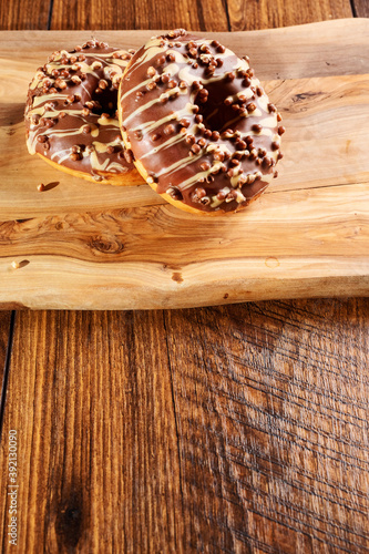 Fresh tasty chocolate with sugar icing donuts on a wooden board. Black background. Bakery product