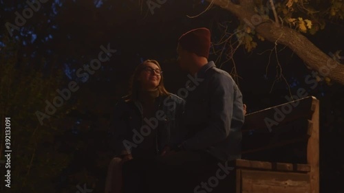 Close up of young couple sits on bentch in night park photo