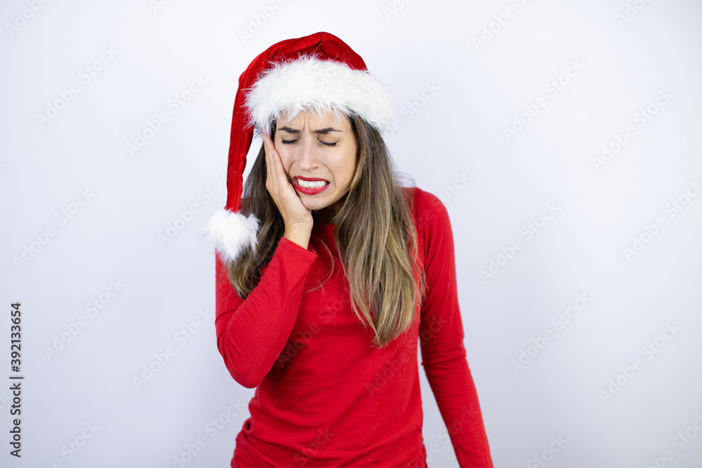 Young beautiful woman wearing a Santa hat over white background touching mouth with hand with painful expression because of toothache or dental illness on teeth