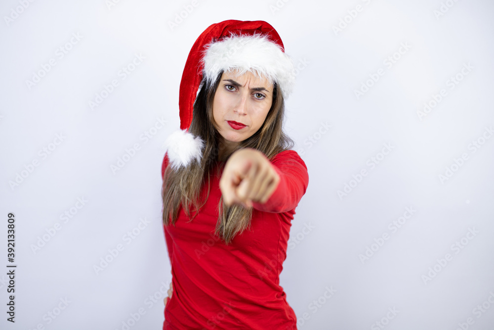 Young beautiful woman wearing a Santa hat over white background pointing to the front with finger Young beautiful woman wearing a Santa hat over white background pointing to the front with finger