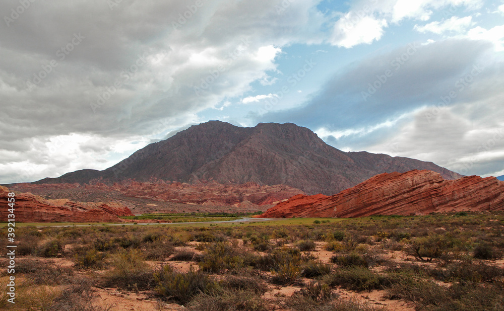 Desert landscape. View of the arid valley, sand, shrubs, red sandstone, rocky formations and mountains at sunset in Quebrada de las Conchas, Salta, Argentina.