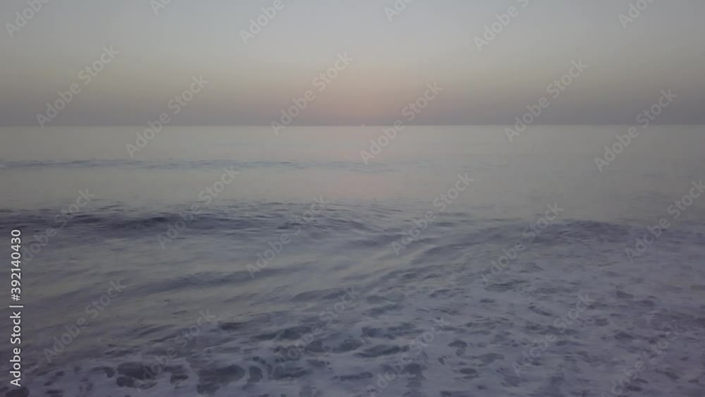 Tilt-down from horizon at sunset to seashore with pebbles . Paul do Mar, Madeira