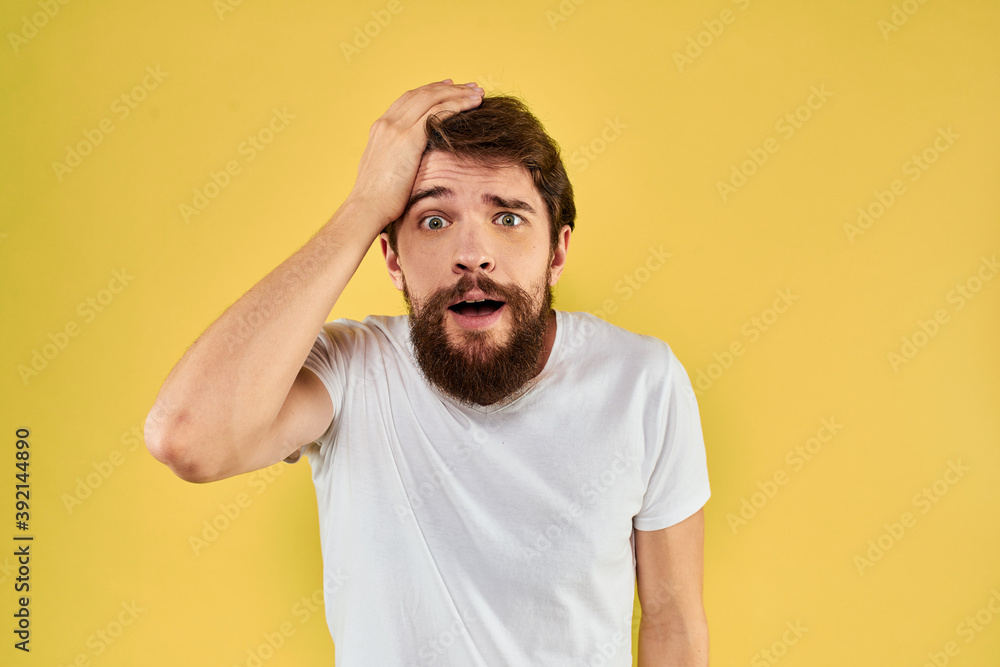 A man in a white t-shirt gestures with his hands lifestyle cropped view yellow background more fun A man in a white t-shirt gestures with his hands lifestyle cropped view yellow background more fun