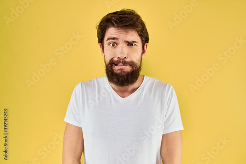 A man in a white t-shirt gestures with his hands lifestyle cropped view yellow background more fun