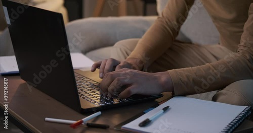 Man working on laptop and writing notes at home office