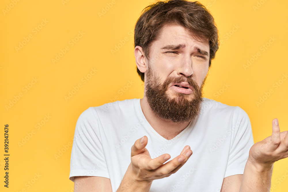 Bearded man emotions gestures with hands facial expression white t-shirt yellow background Bearded man emotions gestures with hands facial expression white t-shirt yellow background