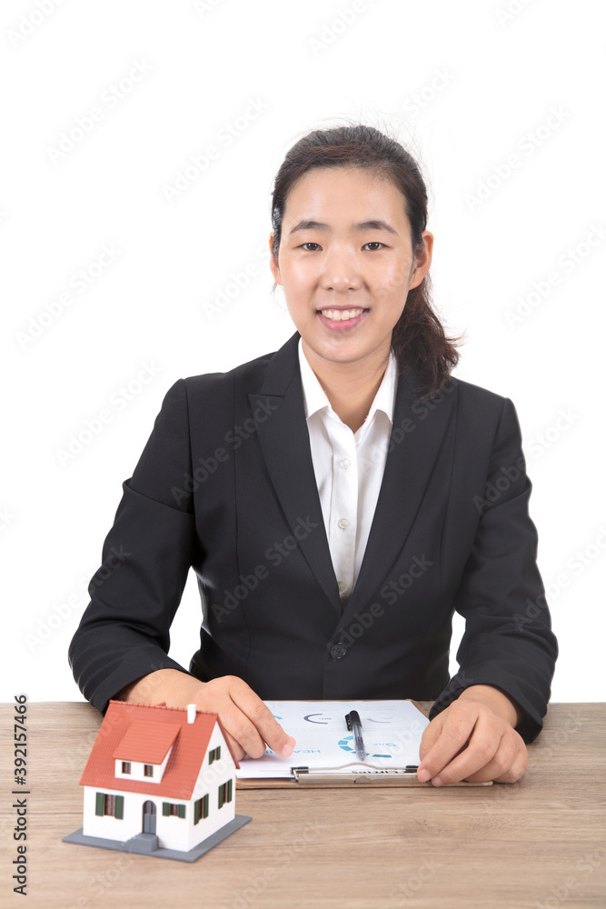 Real estate salesperson sitting at a table with a small house model, looking at the camera and smiling Real estate salesperson sitting at a table with a small house model, looking at the camera and smiling