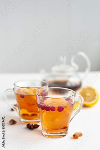 Winter hot tea to strengthen the immune system. Two glass cups in which pour hot tea from the kettle on a white background. Selective focus.