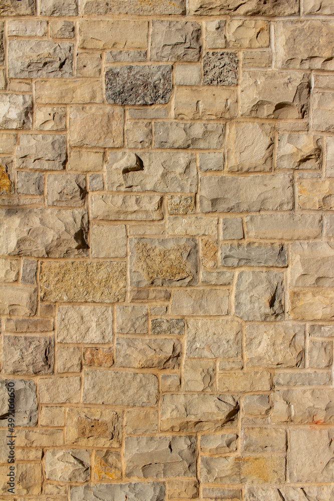 Full frame abstract background of an attractive tan brown natural limestone block wall in ashlar pattern, with rugged texture stone blocks in full sunlight with copy space
