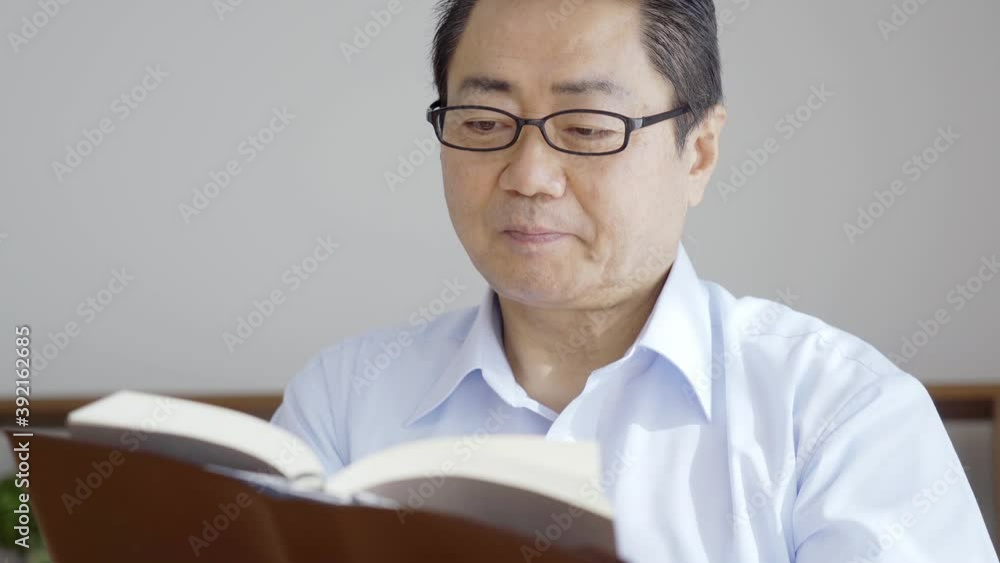 リビングで読書をする中高年男性 リビングで読書をする中高年男性