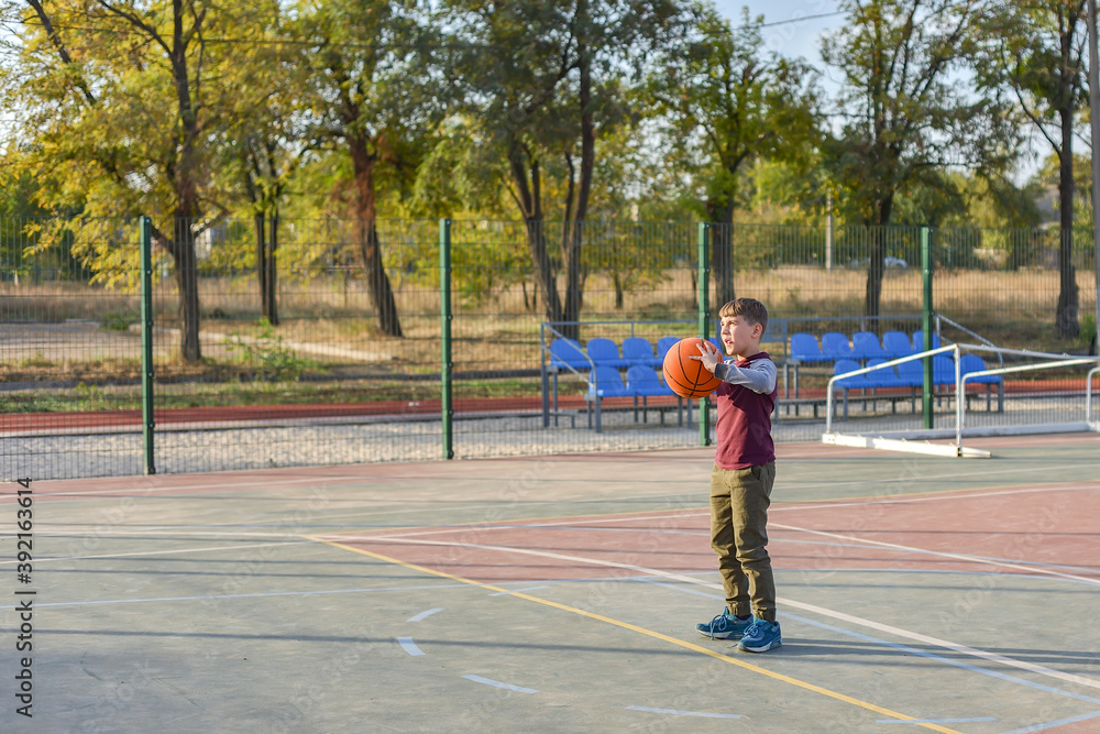 The guy is holding a basketball in his hands and is going to throw it into the hoop on the playground.
