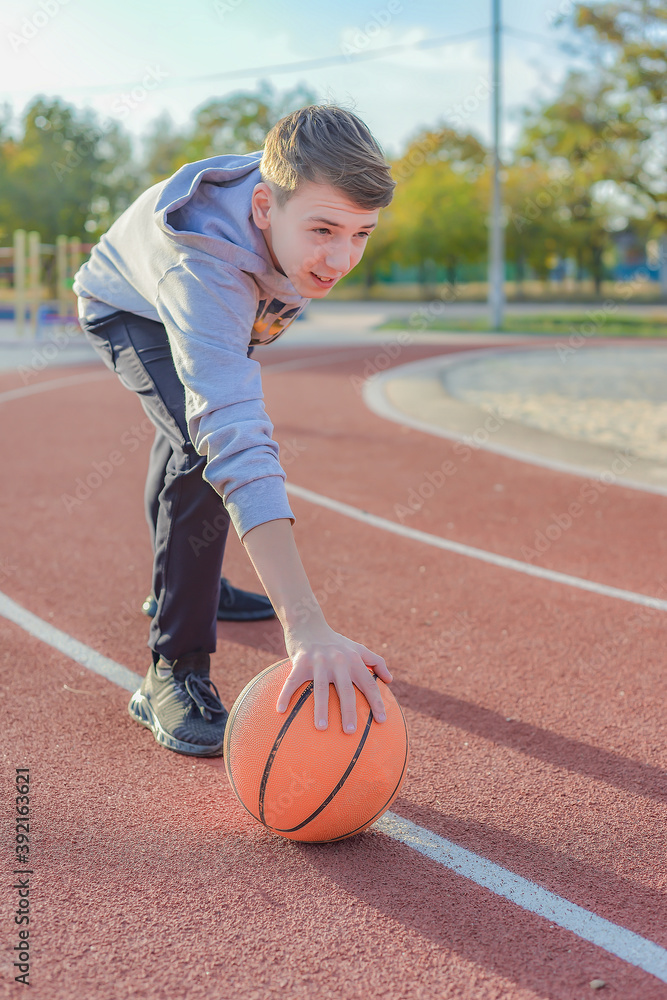 The guy is holding a basketball ball on a red sports field. Sports activities on the playground. The guy is holding a basketball ball on a red sports field. Sports activities on the playground.