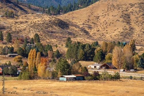 This image shows an idyllic rural Idaho homestead amongst a rolling hills autumn colored landscape.