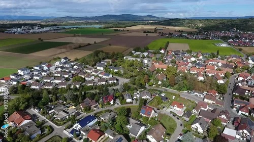 Drone flight over the village of Oberrimsingen on a cloudy summer day, fields, mountains and a lake in the background photo