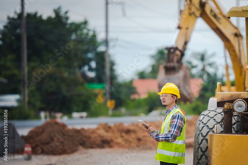 Portrait of a positive happy road worker on the background of heavy equipment