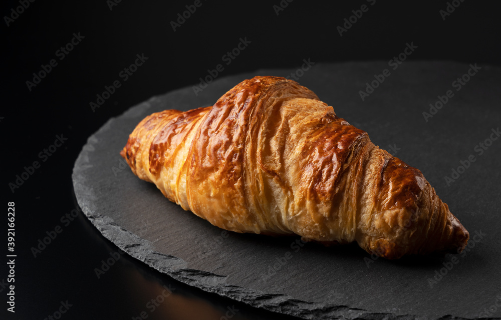Croissant on a black stone plate with a black background