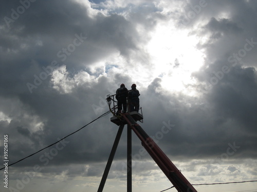
electricians on a lift install a power line on a pole