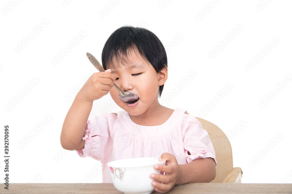 Chinese little girl eating by herself with a spoon Chinese little girl eating by herself with a spoon