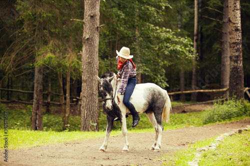 Young girl on the horse in the forest. Equestrian girl. Cowgirl