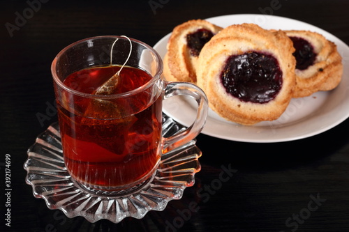 Cup of tea with tea bag and marzipan cookies with jam