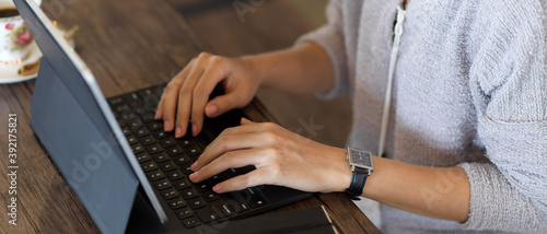 Female hands typing on tablet keyboard on wooden table