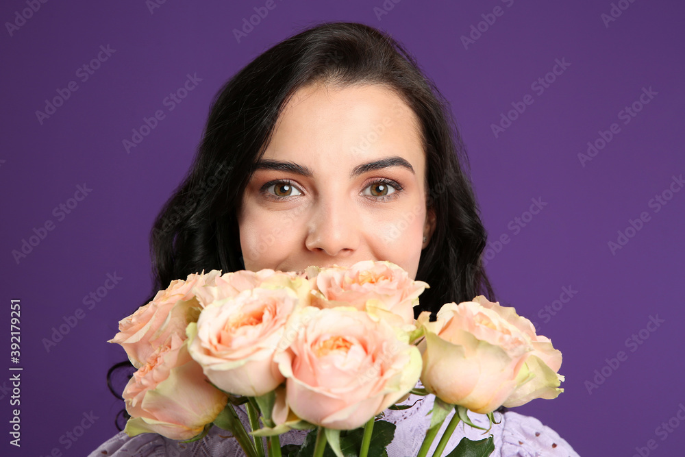 Young woman with beautiful bouquet on purple background