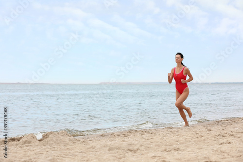 Beautiful female lifeguard running at sandy beach