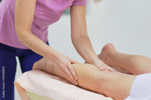 Detail of hands massaging human calf muscle.Therapist applying pressure on female leg. Beautiful girl enjoying treatment procedure  concept of body care and cosmetology
