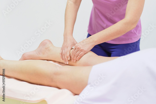 Detail of hands massaging human calf muscle.Therapist applying pressure on female leg. Hands of massage therapist massaging legs of young woman in spa salon. Body care in spa salon for young woman.