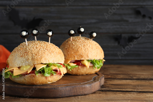 Cute monster burgers served on wooden table, space for text. Halloween party food