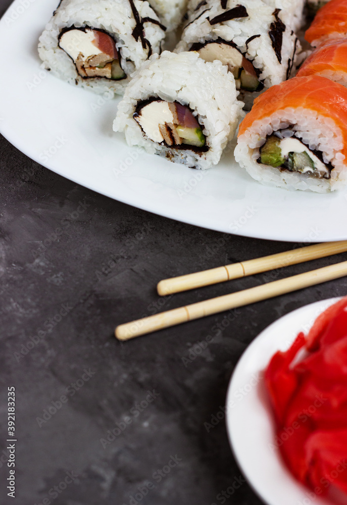 sushi rolls on a white plate on a black background with pickled ginger sushi rolls on a white plate on a black background with pickled ginger