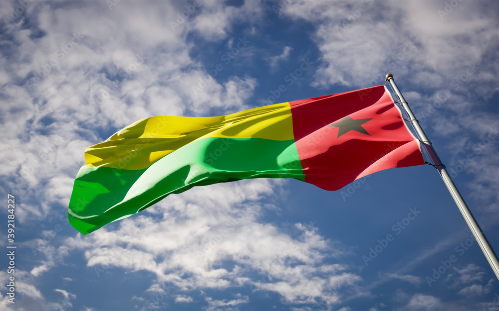Beautiful national state flag of Guinea-Bissau fluttering at sky background. Low angle close-up Guinea-Bissau flag 3D artwork. Beautiful national state flag of Guinea-Bissau fluttering at sky background. Low angle close-up Guinea-Bissau flag 3D artwork.