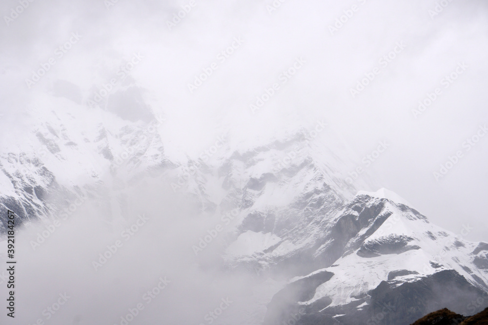 Closeup Mt. Machapuchare in the mist and fog is a mountain in the Annapurna Himalayas of north central Nepal seen from ABC , Nepal - trekking route Adventure Backpacking outdoor Closeup Mt. Machapuchare in the mist and fog is a mountain in the Annapurna Himalayas of north central Nepal seen from ABC , Nepal - trekking route Adventure Backpacking outdoor