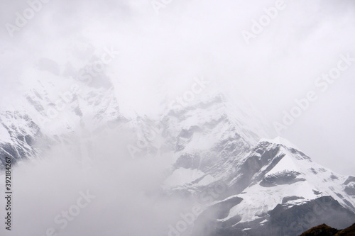 Closeup Mt. Machapuchare in the mist and fog is a mountain in the Annapurna Himalayas of north central Nepal seen from ABC , Nepal - trekking route Adventure Backpacking outdoor 