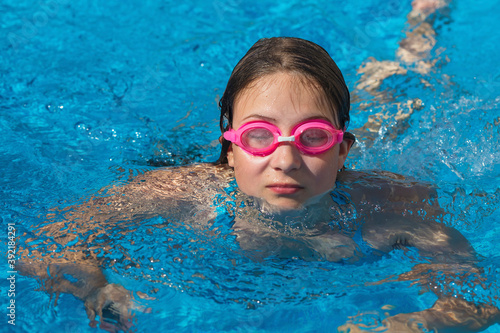 Girl in glasses swim in the blue swimming pool. © idea_studio