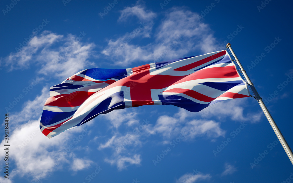 Beautiful national state flag of UK fluttering at sky background. Low angle close-up UK flag 3D artwork.