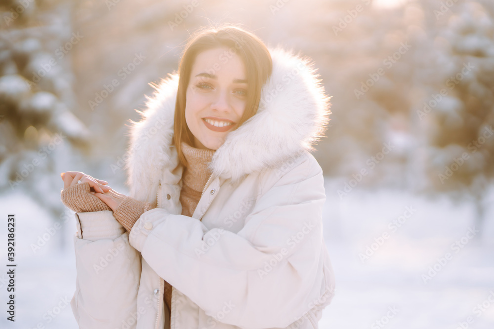 Portrait of young beautiful woman in a snowy park. Cheerful lady in winter clothes posing with joy outside in the snow forest. Winter holiday, Christmas, New year. Portrait of young beautiful woman in a snowy park. Cheerful lady in winter clothes posing with joy outside in the snow forest. Winter holiday, Christmas, New year.