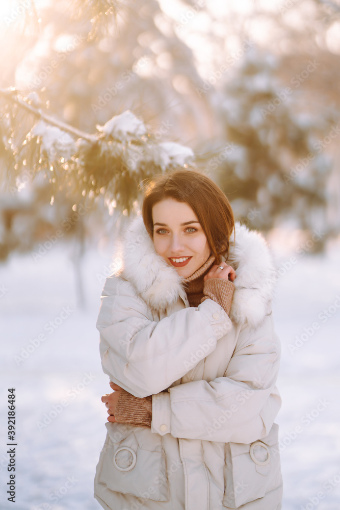 Portrait of young beautiful woman in a snowy park. Cheerful lady in winter clothes posing with joy outside in the snow forest. Winter holiday, Christmas, New year. Portrait of young beautiful woman in a snowy park. Cheerful lady in winter clothes posing with joy outside in the snow forest. Winter holiday, Christmas, New year.