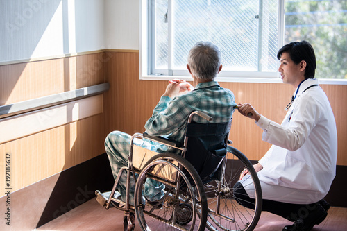 車椅子に乗る高齢男性と医師が会話をしている